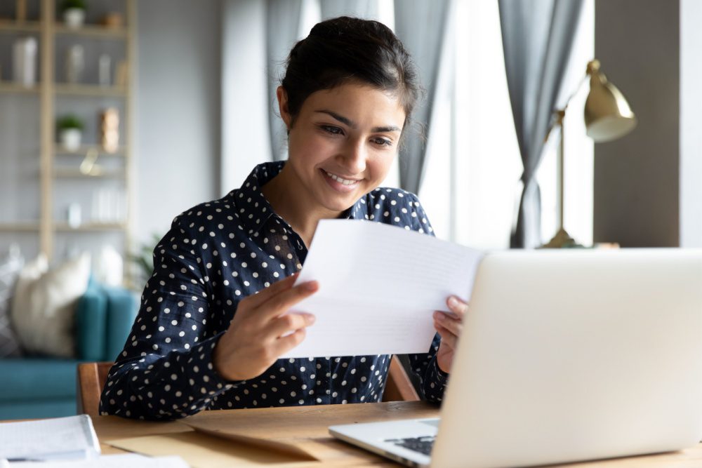 A woman smiling as she looks at paperwork.